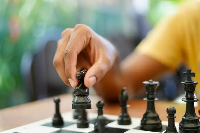 A person holds a chess piece during a game.